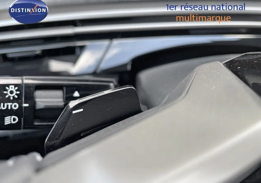 Gros plan sur la commande de feux et la palette de changement de vitesse au volant d'un Peugeot 3008 Hybrid bleu Ingaro Metal.