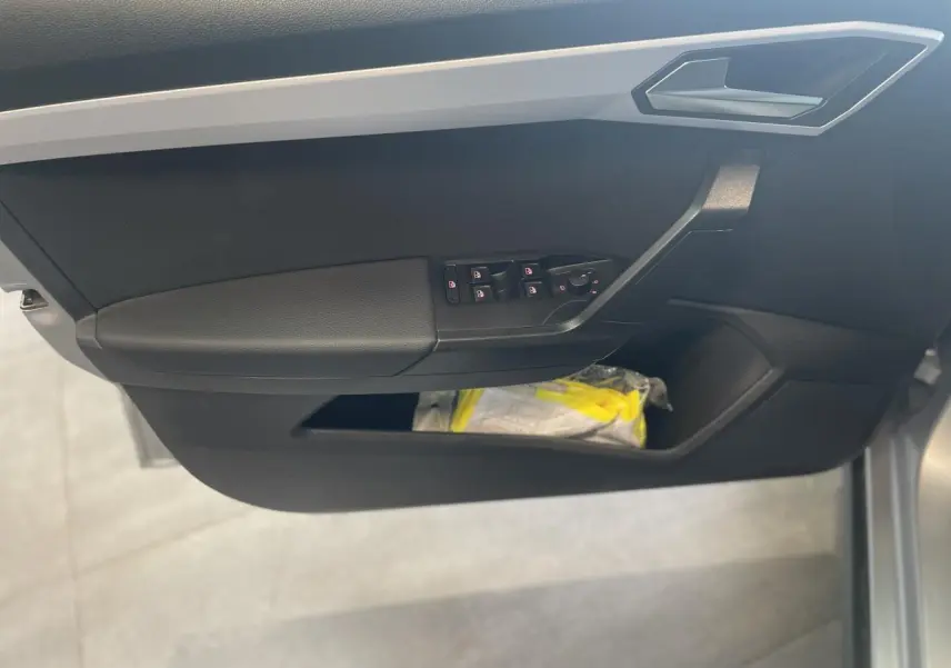 Vue rapprochée de la porte avant gauche de la SEAT ARONA 2024, avec commandes de vitres et rangements noirs.