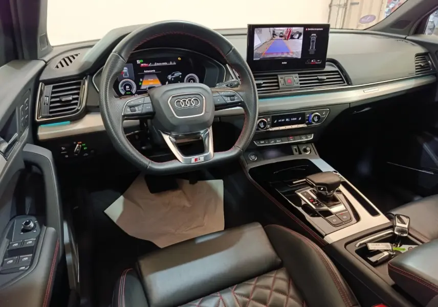 Vue intérieure de l'Audi Q5 2023 hybride rechargeable, avec tableau de bord numérique et volant sport en cuir noir.