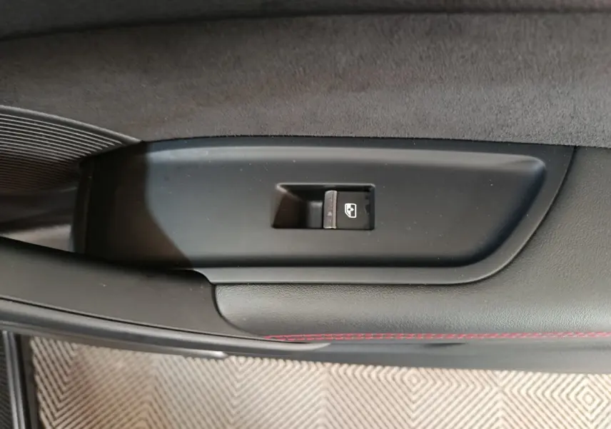 Bouton de commande de lève-vitre sur la porte intérieure noire avec surpiqûres rouges d'un Audi Q5 gris clair hybride rechargeable 2023.