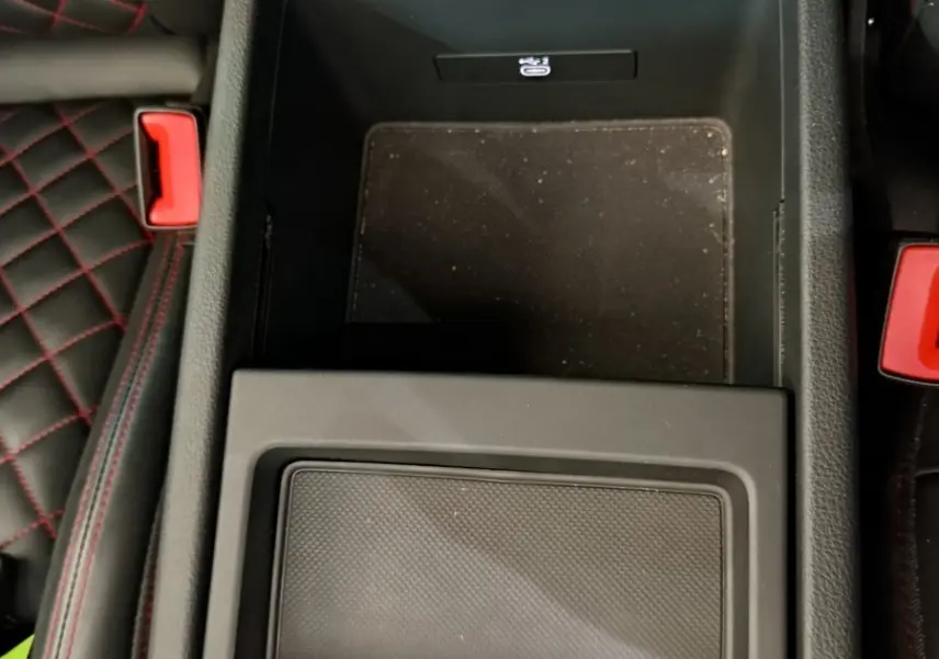 Vue plongeante sur la console centrale noire de l'Audi Q5 2023 avec surpiqûres rouges visibles sur les sièges adjacents.