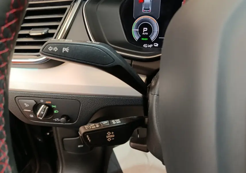 Vue rapprochée du combiné de commandes au volant de l'Audi Q5 2023 gris clair hybride rechargeable, avec affichage numérique.
