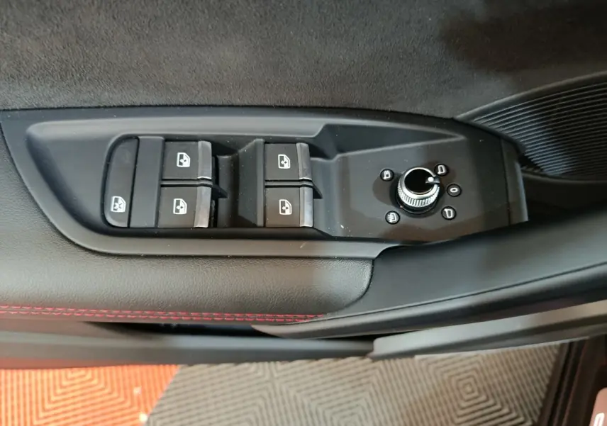 Gros plan sur les commandes de lève-vitres et réglage des rétroviseurs côté conducteur d’un Audi Q5 gris clair 2023.