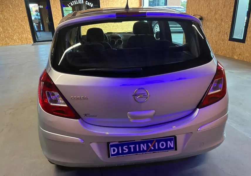 Vue arrière d'une Opel Corsa gris clair de 2012, avec cinq portes et logo distinctif sur le hayon.
