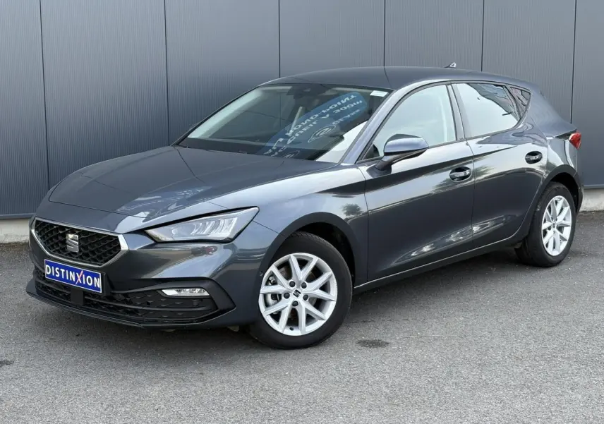 SEAT Leon 2024 gris magnétique vue 3/4 avant droit, avec jantes alliage 16 pouces et vitres arrière surteintées.