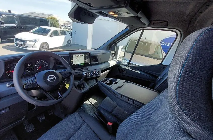 Vue intérieure côté conducteur du Nissan Interstar Fourgon blanc 2025, tableau de bord moderne avec écran tactile et volant multifonction.