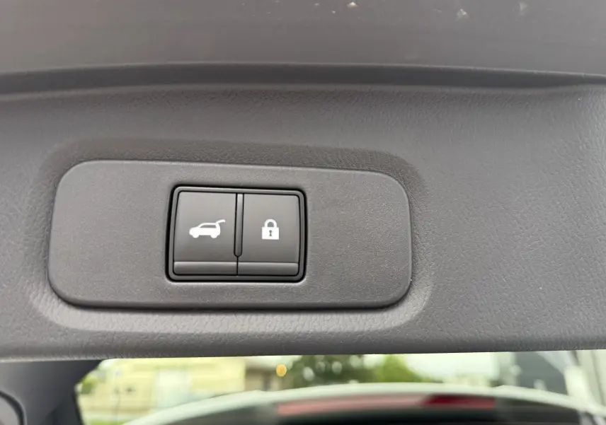 Boutons de commande pour ouverture et verrouillage du hayon sur le panneau intérieur du coffre d'un Nissan Qashqai blanc nacré 2025.