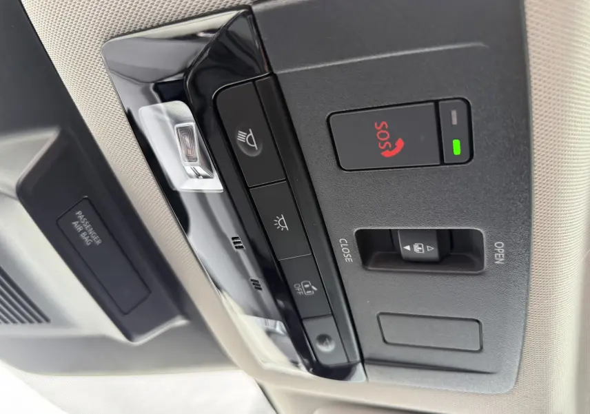 Vue en gros plan du panneau de commandes au plafond du Nissan Qashqai blanc nacré, avec bouton SOS et éclairage intérieur.