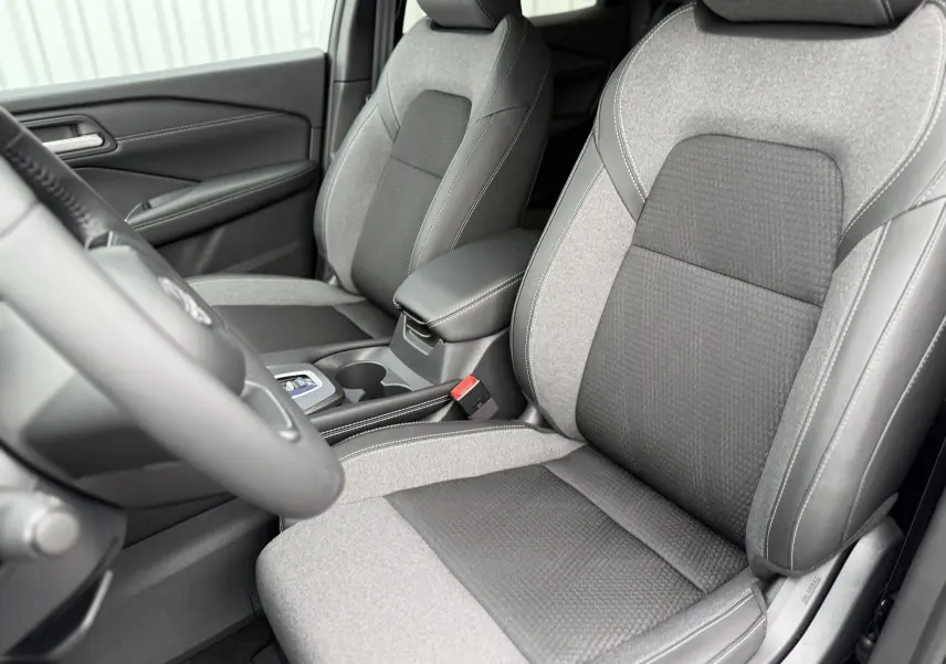 Intérieur du Nissan Qashqai 2025, vue rapprochée des sièges avant en tissu gris et noir avec coutures blanches.