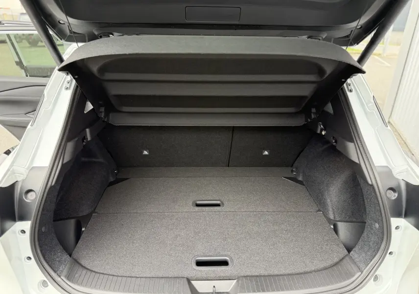 Coffre ouvert du Nissan Qashqai blanc nacré 2025, vue arrière montrant un espace de chargement plat et spacieux.