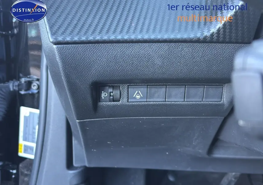 Gros plan sur les commandes noires sous le tableau de bord côté gauche d’un Peugeot 2008 noir 2025.