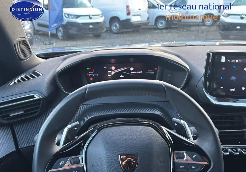 Vue intérieure centrée sur le volant cuir noir et le tableau de bord numérique du Peugeot 2008 1.2 hybrid 145 allure.