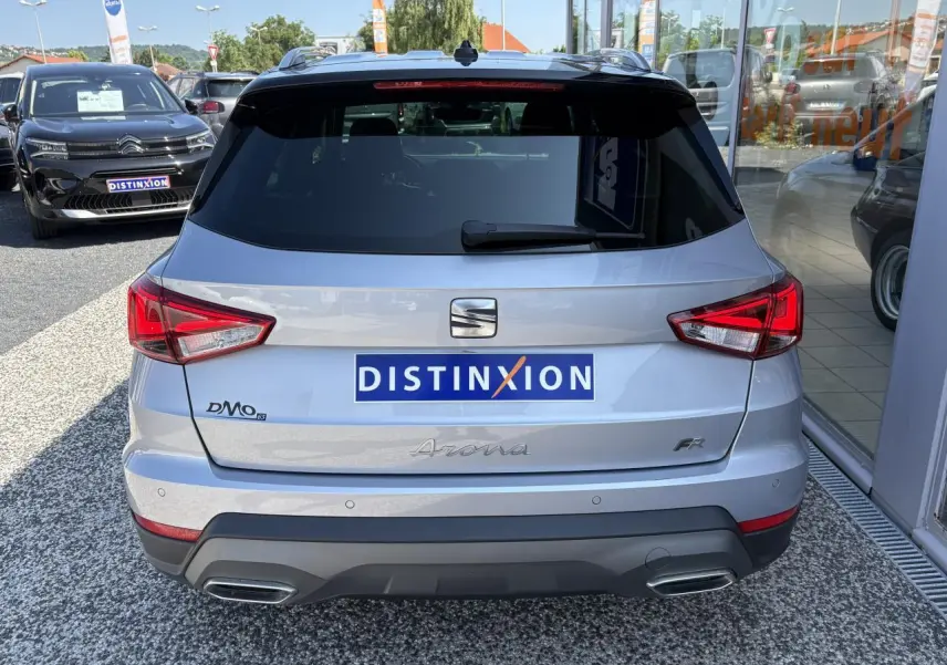 Vue arrière d'une SEAT Arona 2024 gris clair avec logos FR et double sortie d'échappement intégrée.