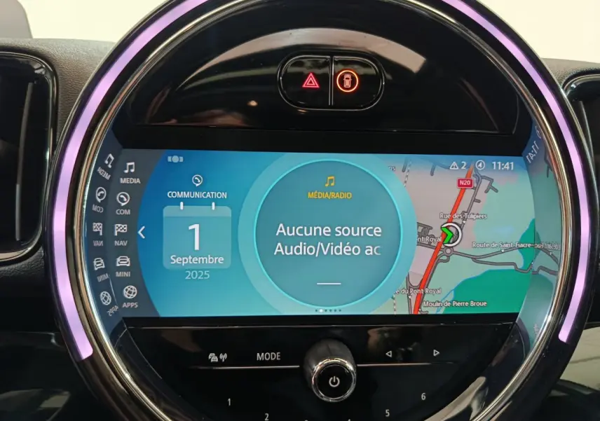 Gros plan sur l'écran tactile circulaire du tableau de bord du MINI Countryman blanc, affichant la navigation et les médias.
