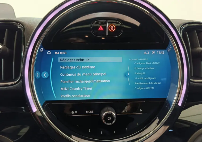 Gros plan sur l'écran tactile central rond du tableau de bord du MINI Countryman blanc, affichant les réglages du véhicule.