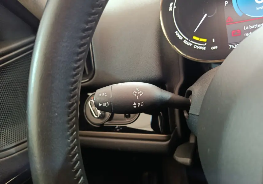 Gros plan sur la commande de clignotant à gauche du volant cuir dans l’habitacle du MINI Countryman blanc hybride rechargeable.