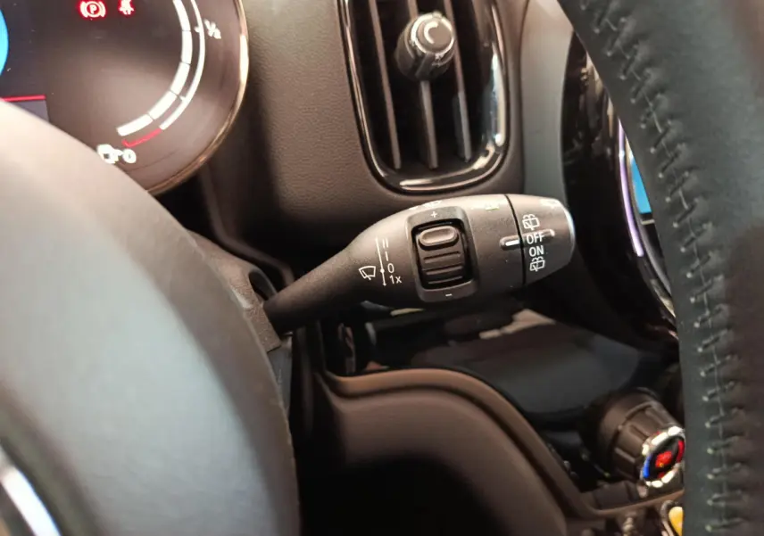 Gros plan sur la commande d’essuie-glace à gauche du volant cuir dans l’habitacle du MINI Countryman blanc.