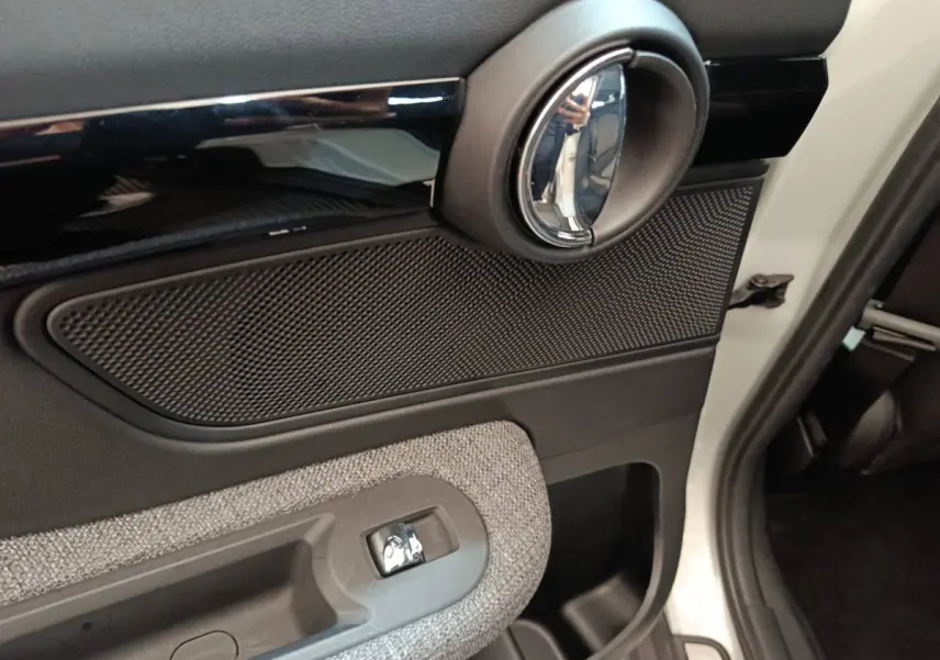 Détail de la porte avant droite blanche du MINI Countryman Cooper SE avec poignée intérieure chromée et tissu gris.