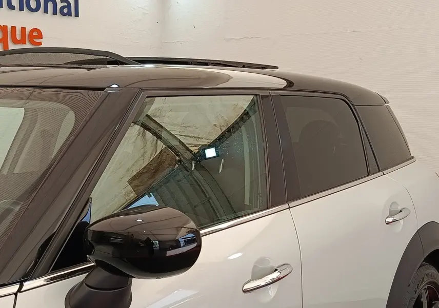 Vue latérale droite d'un MINI Countryman blanc avec toit noir et rétroviseur noir brillant.