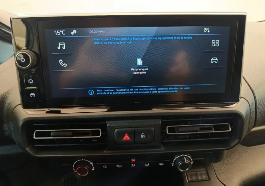 Écran tactile central du tableau de bord du Peugeot Partner 2025 avec commandes de climatisation et boutons de sécurité.