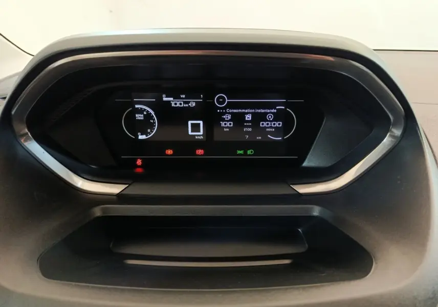 Tableau de bord numérique du Peugeot Partner 2025 affichant la consommation instantanée et les alertes, vue frontale rapprochée.