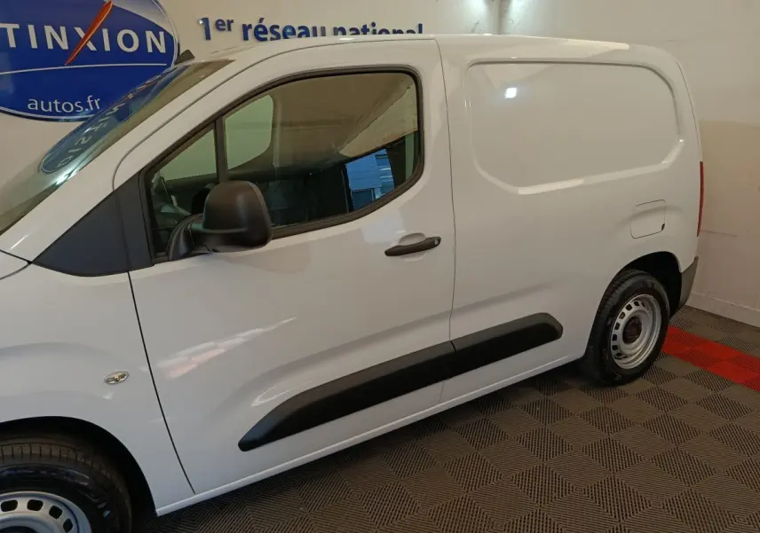 Vue de profil côté gauche du Peugeot Partner blanc, fourgon compact avec porte latérale pleine et rétroviseur noir.