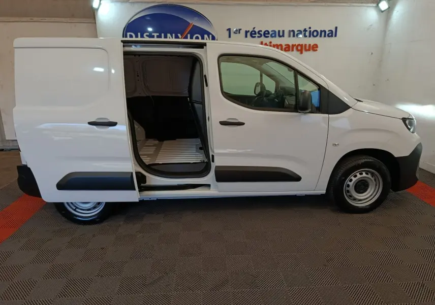 Vue de profil droit d’un Peugeot Partner blanc 2025 avec porte latérale coulissante ouverte montrant l’espace de chargement.