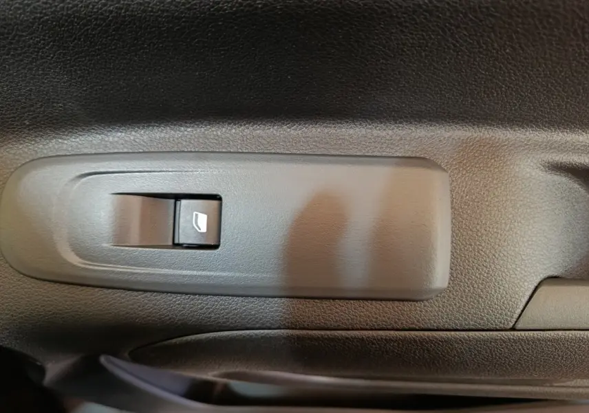 Gros plan sur l'interrupteur de lève-vitre électrique côté conducteur du Peugeot Partner blanc, intérieur noir.