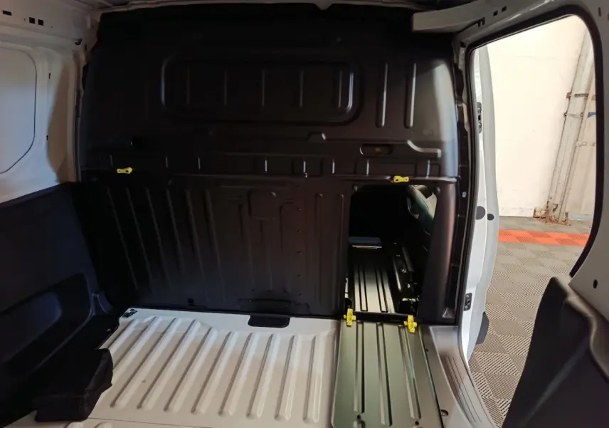 Intérieur du coffre du Peugeot Partner blanc, vue arrière avec cloison pleine et trappe d’accès ouverte côté droit.