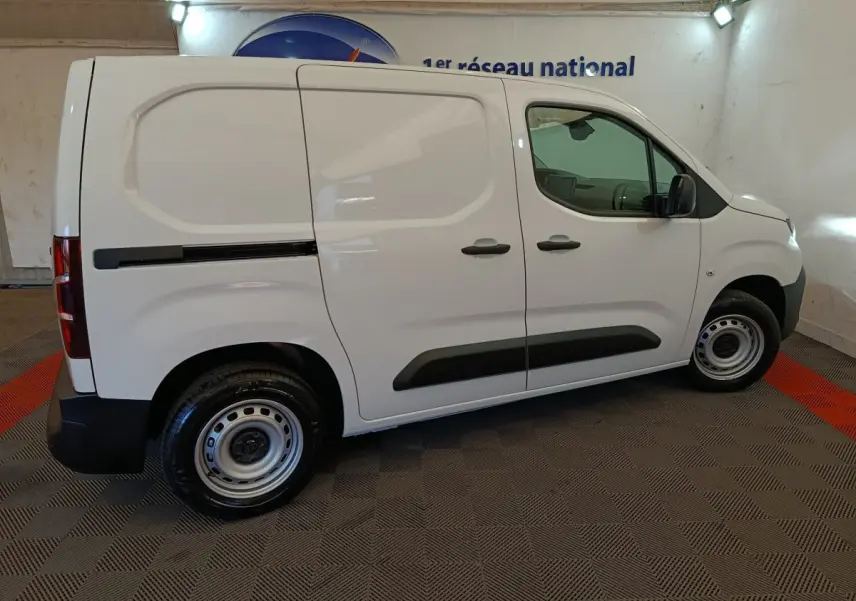 Vue de profil côté droit d’un Peugeot Partner blanc 2025 utilitaire avec protections noires et jantes acier.