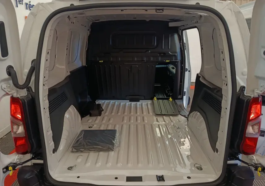 Vue arrière ouverte du Peugeot Partner blanc 2025, montrant l'espace de chargement vide avec cloison pleine noire.