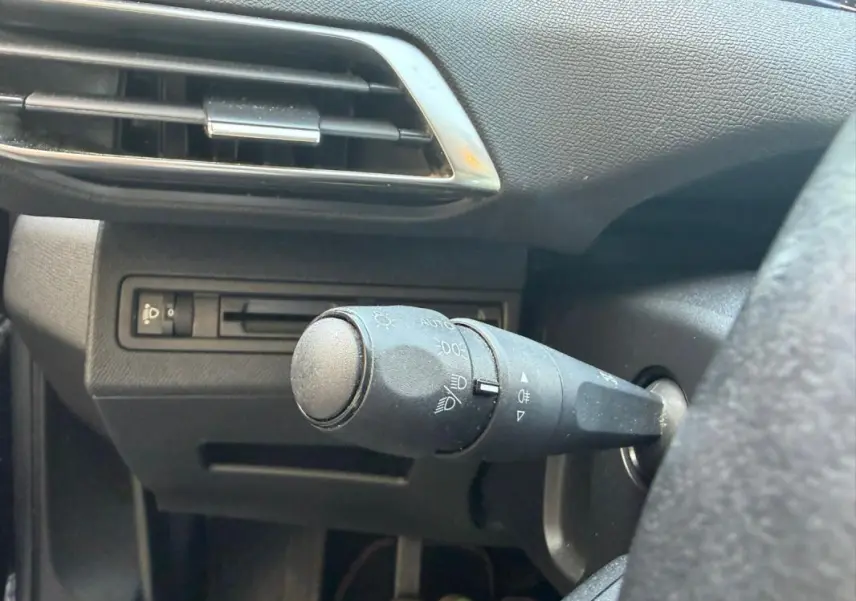 Gros plan sur la commande des phares à gauche du volant dans l’habitacle noir du Peugeot 3008 2021 diesel.