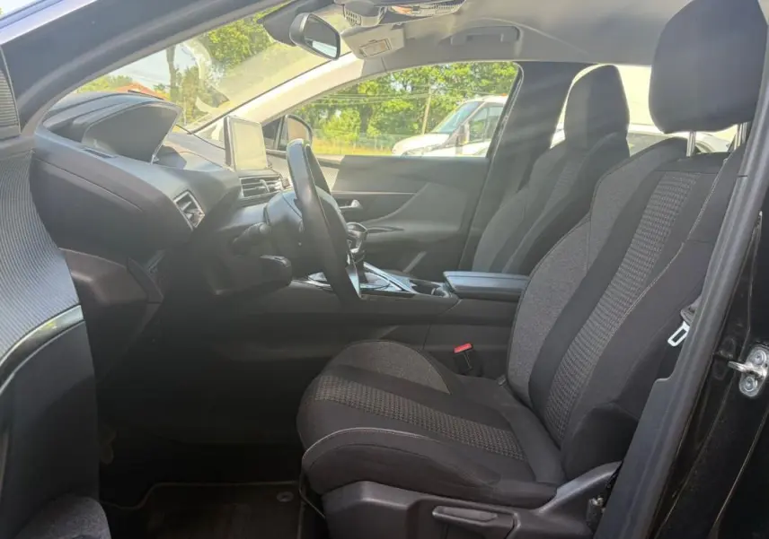Vue intérieure côté conducteur du Peugeot 3008 noir 2021, montrant les sièges tissu et le tableau de bord avec écran central.