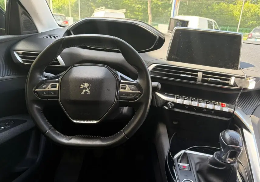 Intérieur du Peugeot 3008 2021 noir, vue centrée sur le volant, tableau de bord et levier de vitesses manuel.
