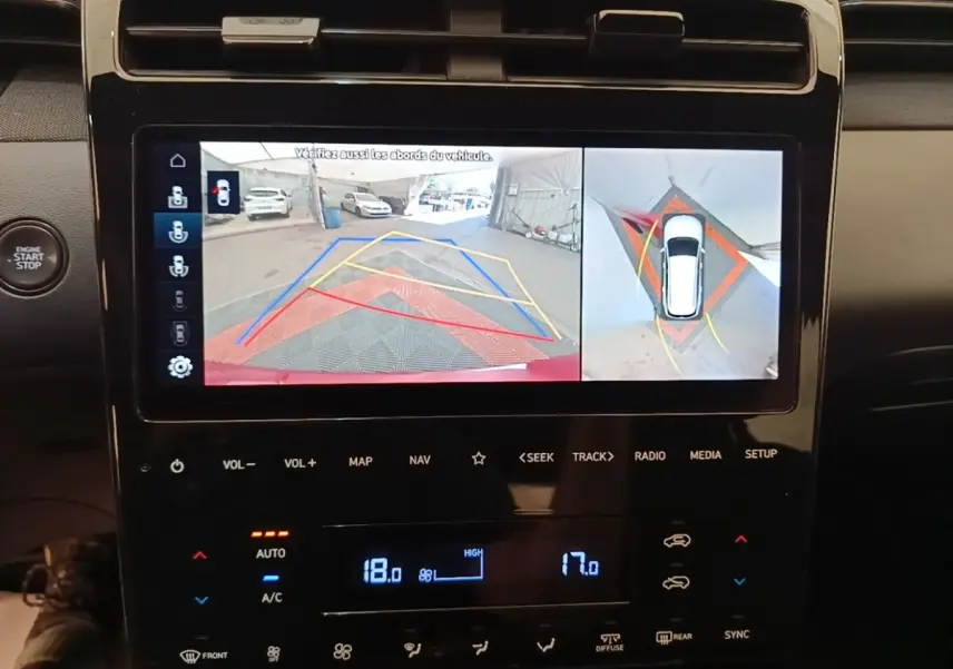 Écran tactile central montrant la caméra 360° et l’aide au stationnement du Hyundai Tucson rouge, vue intérieure.