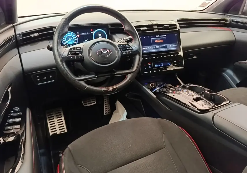 Intérieur noir du Hyundai Tucson 2022, vue avant centrée sur le volant multifonctions et l’écran tactile central.