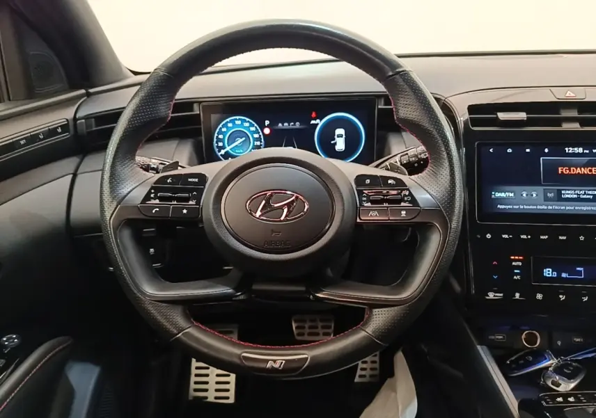 Vue intérieure centrée sur le volant cuir perforé N Line et tableau de bord numérique du Hyundai Tucson 2022.