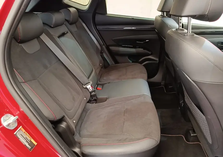 Vue intérieure côté gauche des sièges arrière en tissu et cuir noir avec surpiqûres rouges d’un Hyundai Tucson rouge.