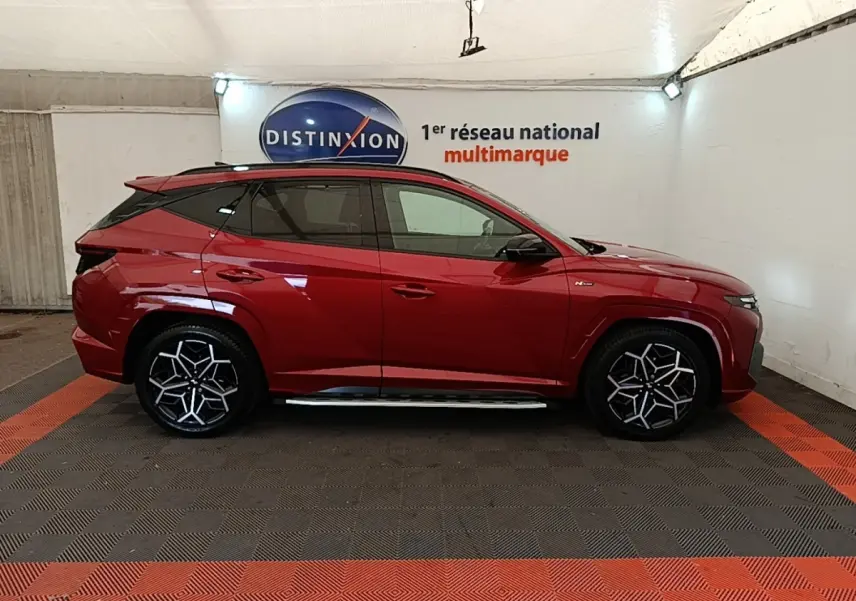 Hyundai Tucson rouge vue de profil côté gauche, avec jantes noires et argentées au design distinctif N Line.