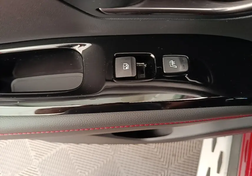 Détail de la commande de verrouillage et siège chauffant sur la porte intérieure d’un Hyundai Tucson rouge.