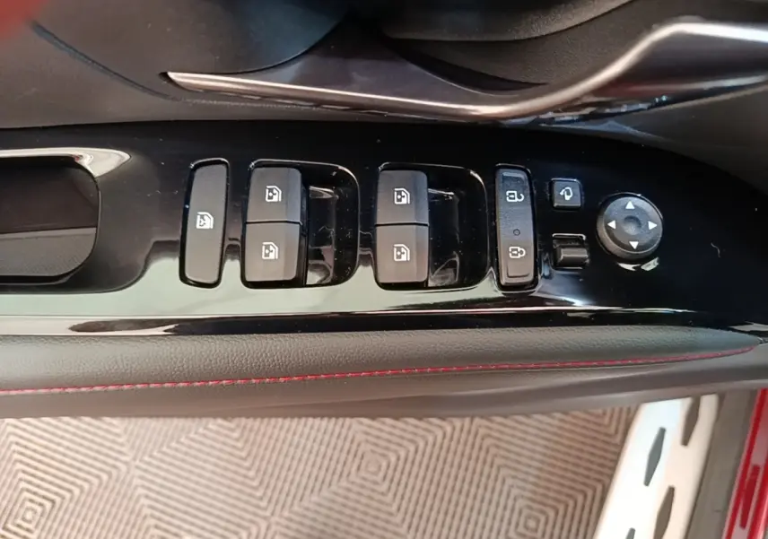 Gros plan sur les commandes de lève-vitres et rétroviseurs côté conducteur du Hyundai Tucson rouge, finition N Line.
