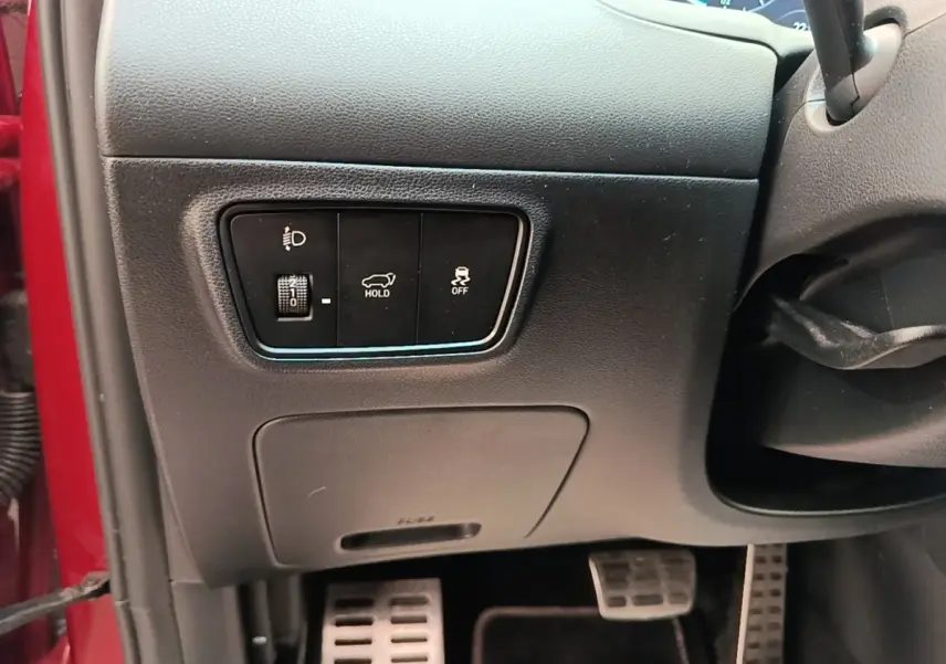Détail intérieur côté gauche tableau de bord rouge Hyundai Tucson 2022 avec commandes éclairage et maintien frein.