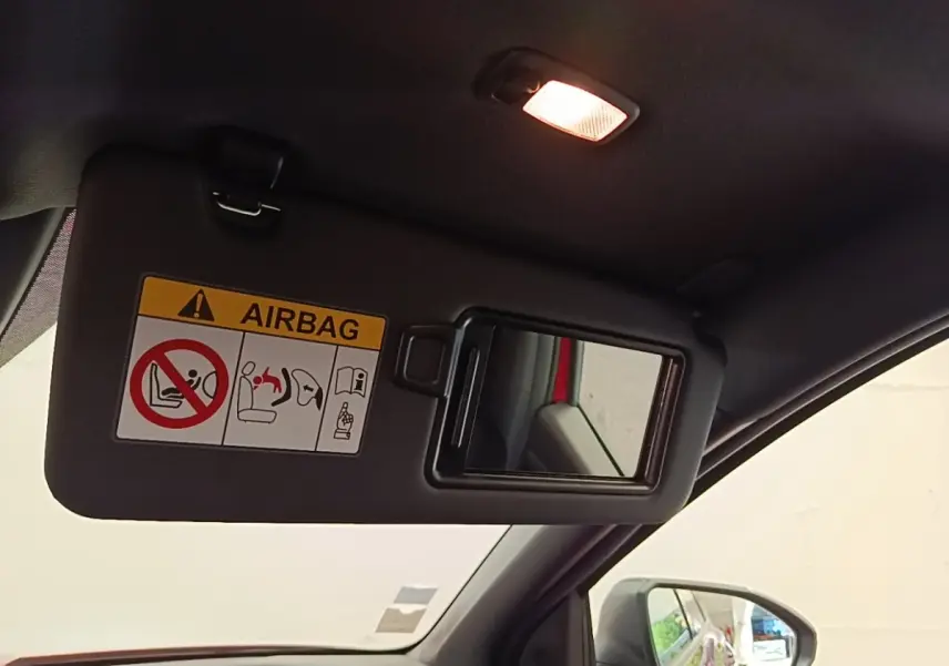 Détail du pare-soleil côté conducteur avec miroir intégré et avertissement airbag, intérieur noir du Hyundai Tucson rouge.