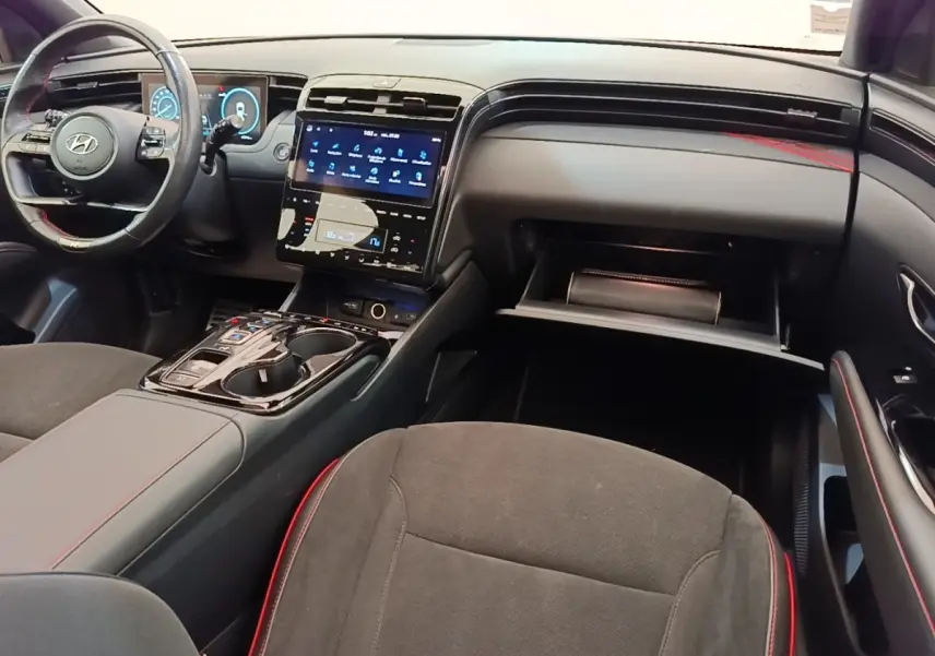 Intérieur noir et rouge du Hyundai Tucson 2022, vue de côté droit sur le tableau de bord et console centrale tactile.