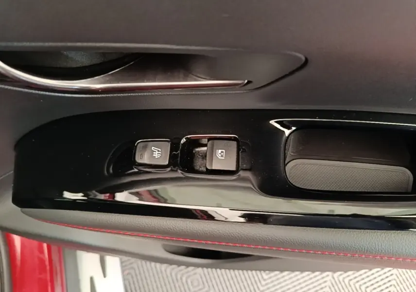 Gros plan sur la commande de lève-vitre et siège chauffant côté conducteur d’un Hyundai Tucson rouge.