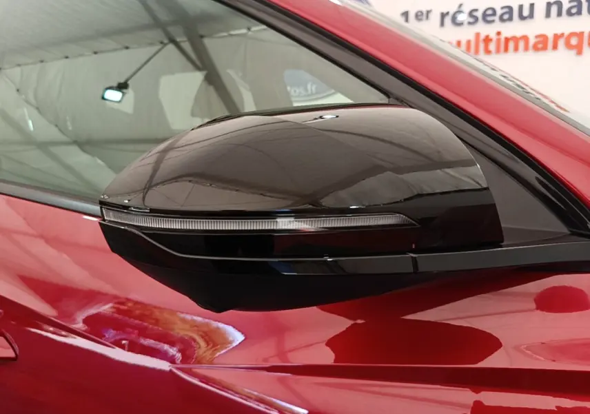Rétroviseur latéral droit noir brillant sur Hyundai Tucson rouge, vue rapprochée sur la porte avant.