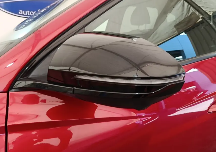 Gros plan sur le rétroviseur droit noir brillant du Hyundai Tucson rouge, mettant en valeur le clignotant intégré.