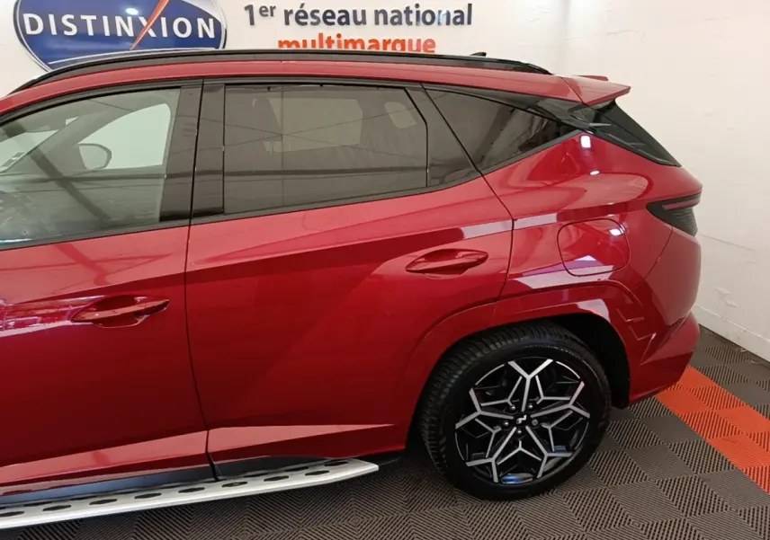 Vue latérale droite du Hyundai Tucson rouge 2022 avec jante alliage noire et détails de carrosserie anguleux.