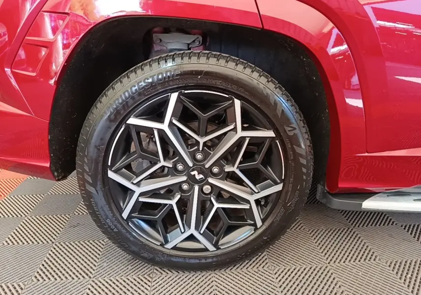 Gros plan sur la roue arrière droite rouge d’un Hyundai Tucson 1.6 CRDI N Line avec jante alliage noire et argentée.