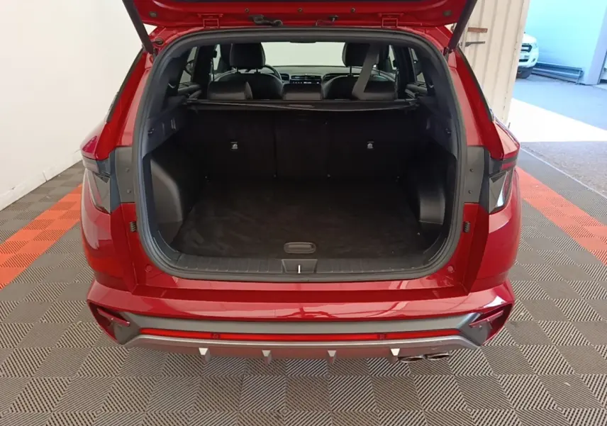 Vue arrière ouverte du coffre d'un Hyundai Tucson rouge 2022, montrant l'espace de chargement et l'intérieur sombre.